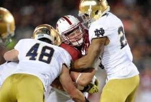 Stanford Cardinal running back Christian McCaffrey (5) is brought down by Notre Dame Fighting Irish linebacker Greer Martini (48) and safety Elijah Shumate (22) during the first half at Stanford Stadium.